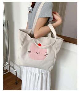 Détail du sac cabas en velours beige avec broderie de chat rose et accents cerise