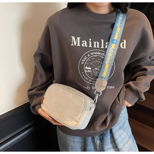 Detail of beige canvas crossbody camera bag with trendy colorful jacquard wide strap