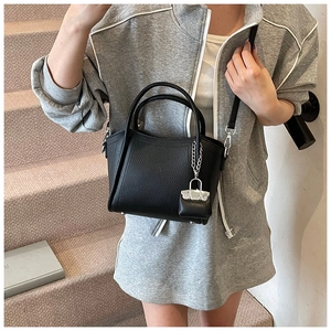 Litchi pattern black bucket bag with silver chain detail shown in a street lifestyle setting