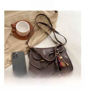 Close-up of vintage brown leather crossbody bag with tennis racket charm and tassels