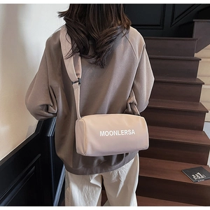 Detail of beige canvas pillow bag with wide strap and Moonlersa text logo on back