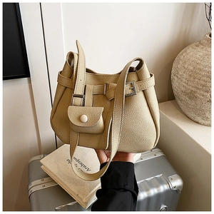 Detail of beige leather bucket bag featuring a mini pouch on a silver suitcase