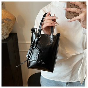Close-up of glossy patent leather mini bucket bag with chic puppy charm and handle