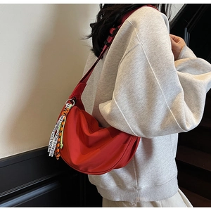 Detail of red crescent nylon shoulder bag with decorative woven strap and adjustable belt