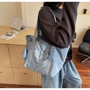 Detail of light blue nylon tote bag with metal eyelet strap and matching coin purse