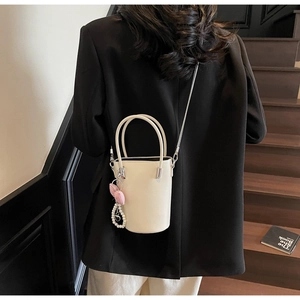 Schicke cremefarbene Leder-Beuteltasche mit Herzanhänger und Perlenkette am Model