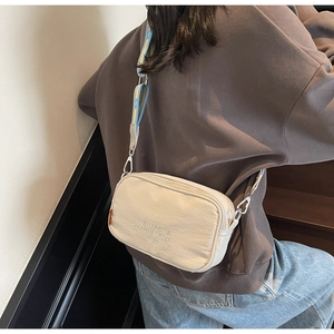 Detail of canvas camera bag with wide jacquard strap and dream embroidery