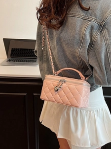 Pink quilted crossbody bag with gold chain strap and heart charm in office setting
