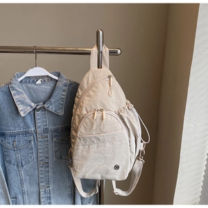 Detail view of cream nylon chest bag with adjustable strap and drawstring pocket