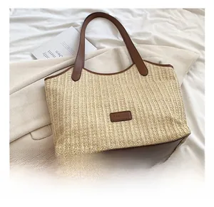 Vue détaillée du sac cabas en paille avec poignées en cuir marron et patch logo fashion
