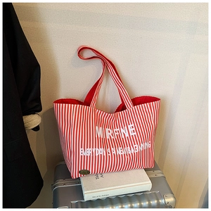 Detail of red and white striped canvas tote bag with MRFNE logo on a travel suitcase