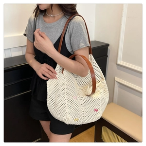 Close-up of white crochet tote bag featuring colorful bows and brown leather handles