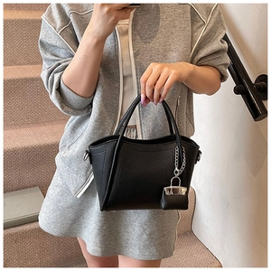 Detail of black lychee grain leather bucket bag with a mini pouch charm and silver hardware