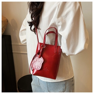 Detail of red glossy mini bucket bag with cute dog charm and detachable shoulder strap