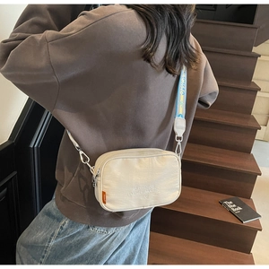Detail view of stylish cream canvas camera bag with patterned strap on model