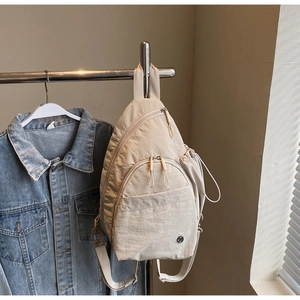 Close-up of oatmeal nylon sling bag with drawstring side pocket and adjustable strap