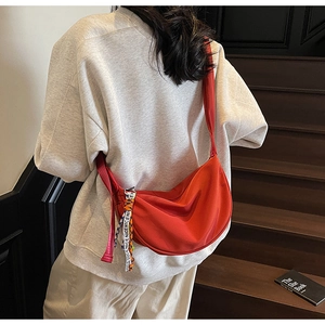 Macro detail of vibrant orange moon bag with a decorative patterned silk scarf handle
