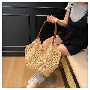 Detail of beige woven tote bag featuring colorful 3D bow accents and slim brown leather handles