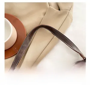 Detail of vintage brown leather bag strap with white contrast stitching and gold buckle