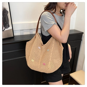 Detailed view of woven straw tote bag with pastel bow charms and leather straps