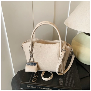 Detailed macro shot of beige pebble leather handbag with fine stitching and mini bag charm