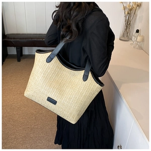 Détail du sac cabas en paille avec lanières en cuir noir et étiquette de mode porté