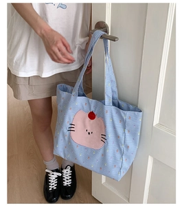 Détail du sac cabas à carreaux bleus avec broderie chat rose et petit accent cerise