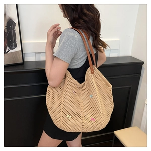 Detail of woven beige tote bag featuring colorful ribbon bows and brown leather straps
