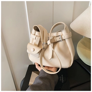 Detail of creamy white pebble grain leather bag featuring a functional small coin pouch