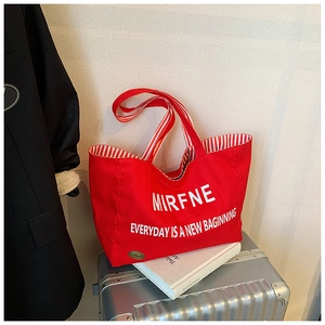 Close-up of a red canvas tote bag with white lettering and striped inner lining