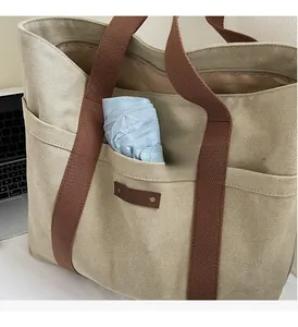 Detail of canvas tote bag showing large front pocket storage with a blue umbrella