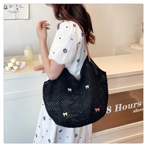 Detailed view of black crochet knit hobo bag with colorful bow patches and leather straps