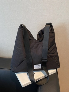 Black quilted nylon crossbody bag with adjustable wide strap and minimalist brand label