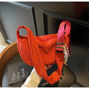 Detail of red nylon hobo bag with a decorative bohemian woven scarf on the shoulder strap