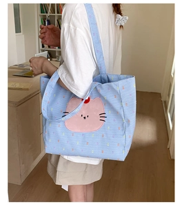 Détail du grand sac cabas en toile à carreaux bleus avec motif de chat rose et bandoulière