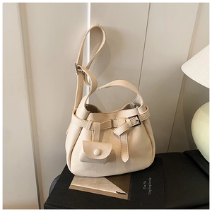 Close-up of creamy white lychee textured bucket bag with decorative buckle and mini pouch