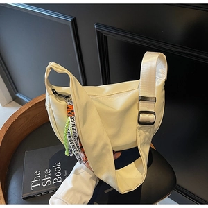Detailed close-up of white half-moon nylon bag with wide strap and decorative NICE ribbon