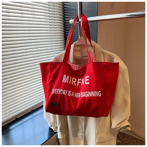 Detail of red canvas tote bag with white lettering and striped lining on a hanger