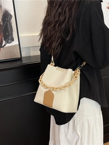 Sac seau beige chic avec chaîne en résine et accents en cuir marron sur un mannequin