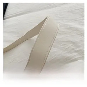 Detail of beige faux leather bag strap featuring double stitching and pebbled texture