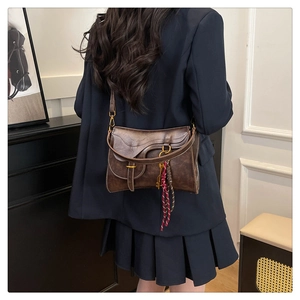 Detail of vintage brown saddle bag showing frosted texture and woven tassel decoration
