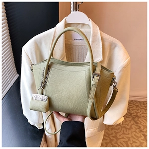 Close-up of sage green litchi grain bucket bag featuring a mini pouch charm and silver chain
