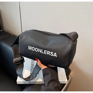 Detail of black canvas cylinder bag with Moonlersa lettering and wide strap