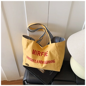 Detail of yellow canvas tote bag with blue striped lining and interior circular label