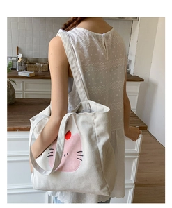 Détail du sac cabas en velours côtelé blanc avec motif chat rose dans une cuisine