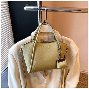 Detail of lime green litchi texture handbag on beige blazer with mini pouch accessory