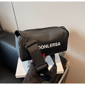 Detail of black nylon boston bag with white logo lettering and wide shoulder strap