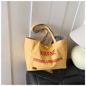 Detail of yellow canvas tote with red lettering and blue striped fabric lining