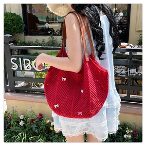 Detail of red crochet tote bag with colorful bows and brown leather straps