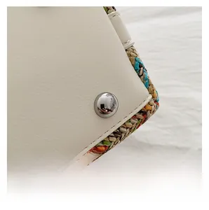 Close-up of woven straw texture and protective metal studs on ivory leather handbag